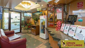 A hotel lobby with a reception desk, seating area, and a refrigerator stocked with beverages. - Hotel Gran Quitumbe (Quito)