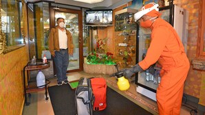 A hotel lobby with a reception desk, a television mounted on the wall, and a decorative display with flowers and a statue. - Hotel Gran Quitumbe (Quito)