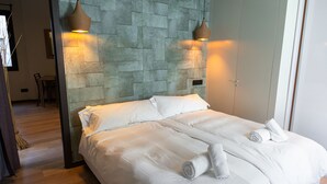 Une chambre d’hôtel avec un grand lit, deux lampes fixées au mur et un mur à la texture de pierre.