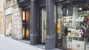 Un immeuble dont le rez-de-chaussée abrite une boutique appelée « Handmad », où sont exposées des œuvres d’art et vendus des souvenirs.