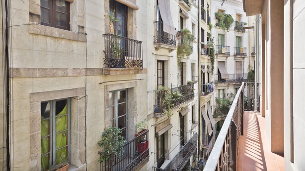 Un immeuble à plusieurs étages, doté de balcons, de plantes en pot et d’un couloir étroit.