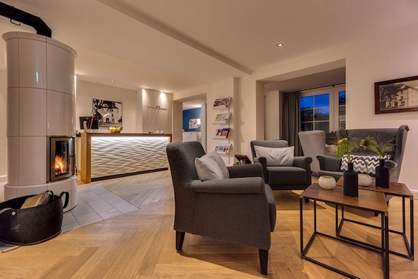 Una sala de estar moderna con chimenea, asientos cómodos y una cocina al fondo.
