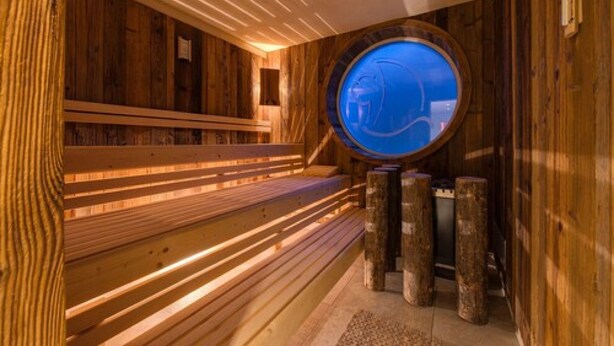 Puisesta laudelavasta ja pyöreästä ikkunasta koostuva sauna.