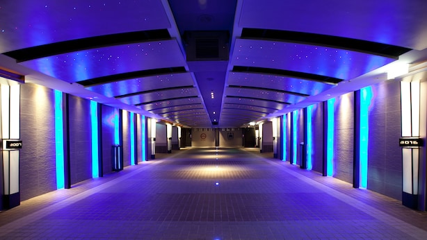 Un pasillo largo y estrecho con diseño moderno, paredes iluminadas y suelo de baldosas.