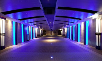 Een lange, smalle gang met een modern ontwerp, met verlichte wanden en een betegelde vloer.