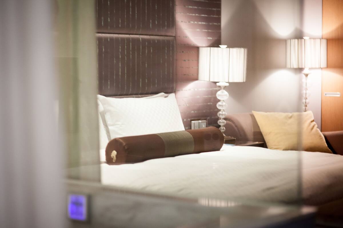 A hotel room with a bed, a nightstand, a lamp, and a headboard.