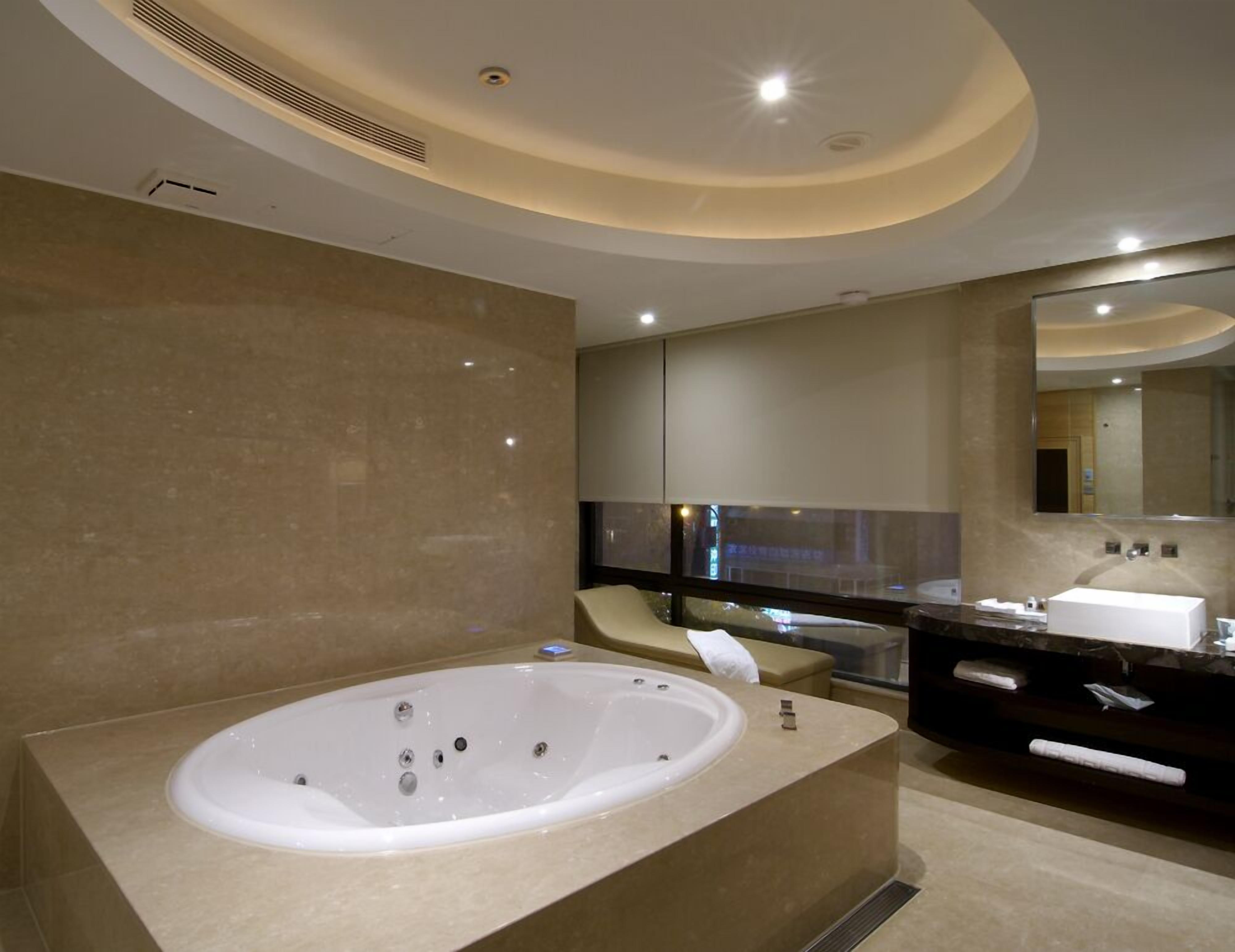A modern bathroom with a large freestanding bathtub, a vanity with a mirror, and a recessed ceiling light.