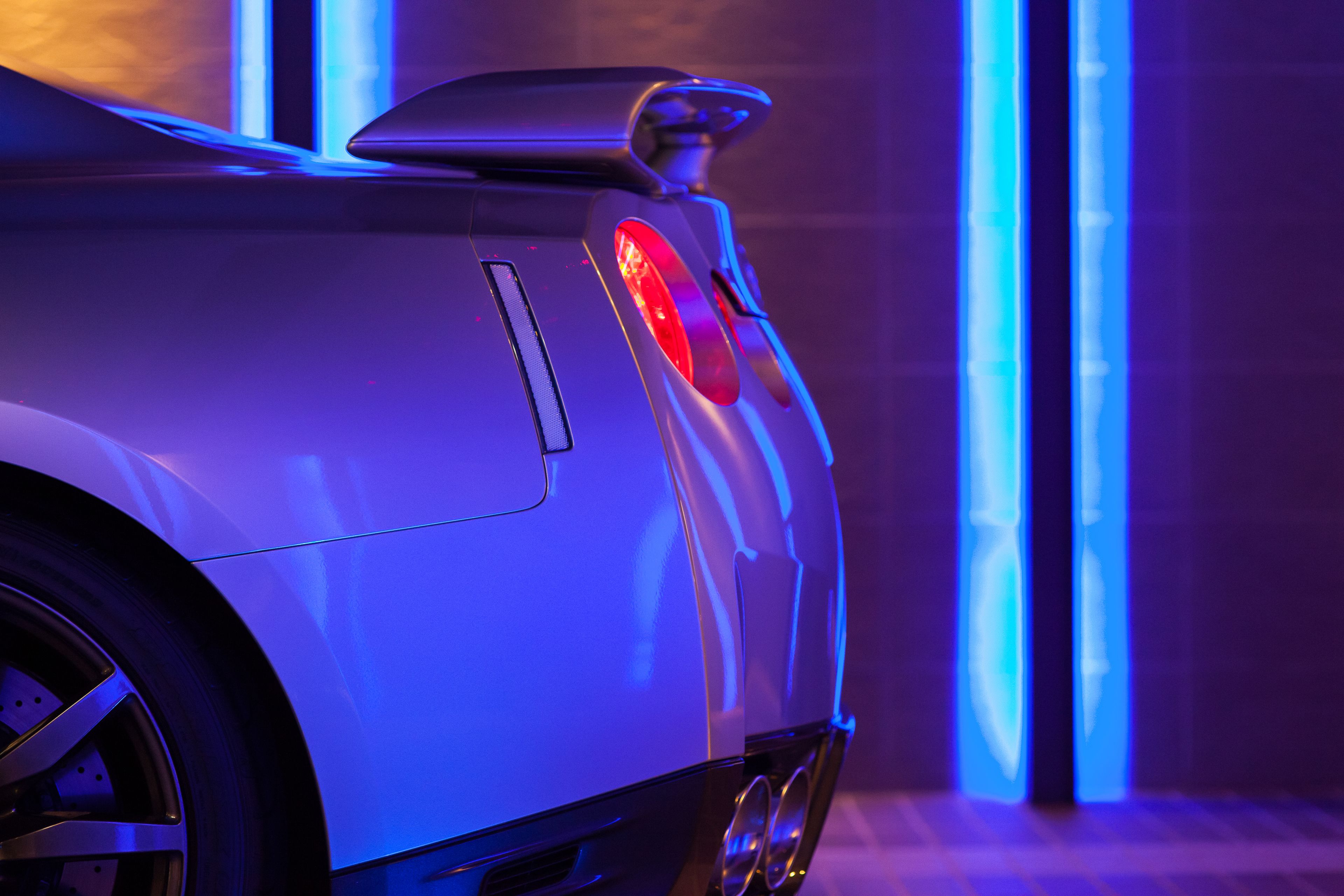 A close-up of a car's rear with a spoiler, taillights, and a vent.