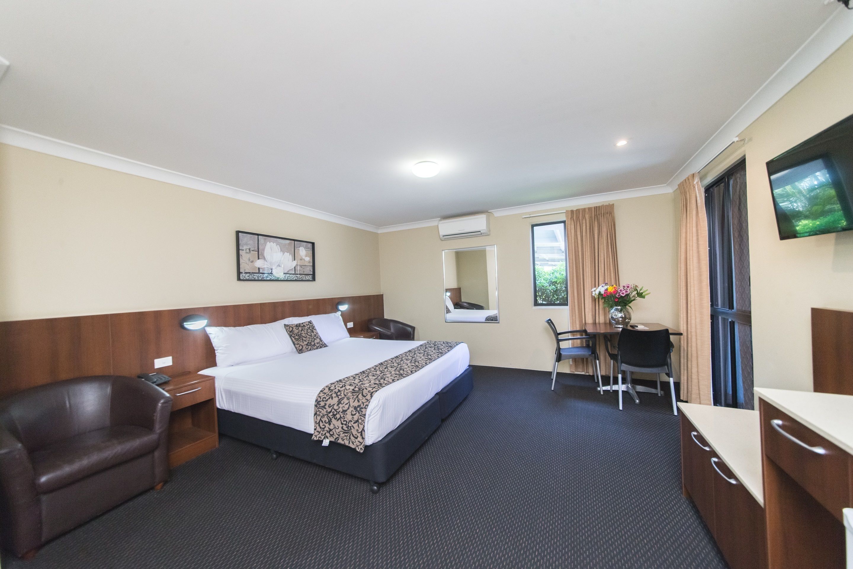 Hotelkamer met een groot bed, een bureau, een stoel, een televisie en een raam met gordijnen.