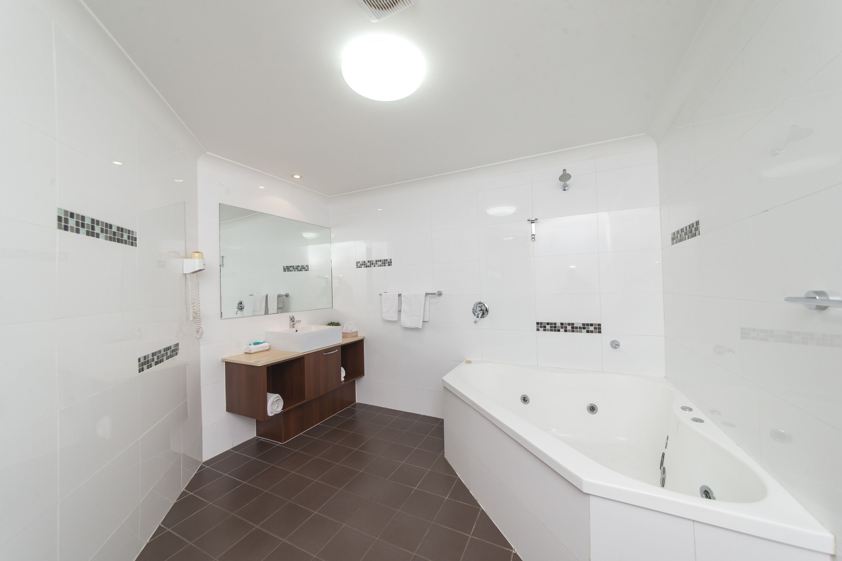 Une salle de bain moderne avec une grande baignoire, un meuble-lavabo avec un miroir et un espace douche.