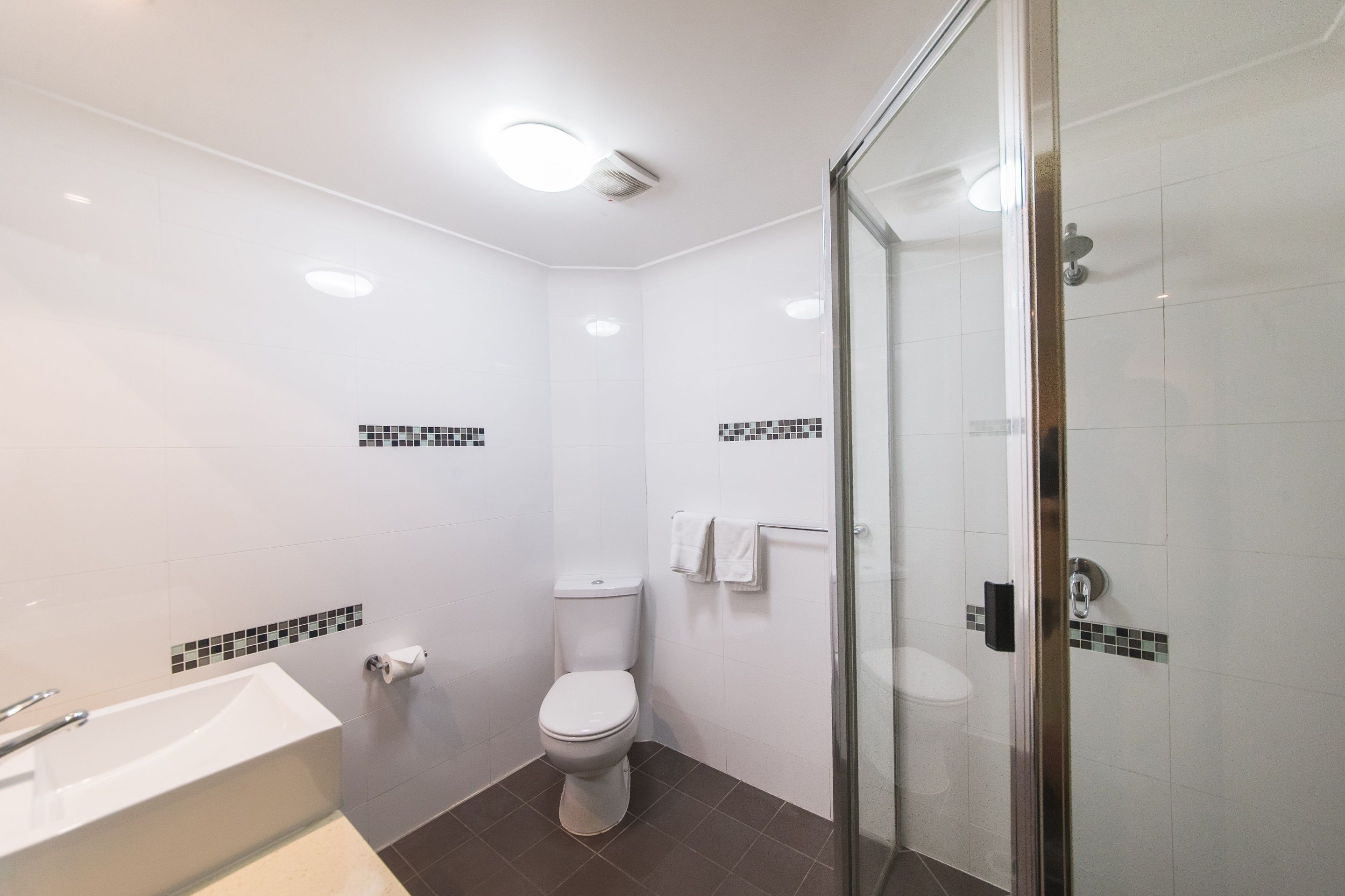 A modern bathroom with a bathtub, toilet, and glass shower enclosure.
