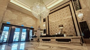Un vestíbulo con candelabro, mostrador de recepción y pared con diseño geométrico.