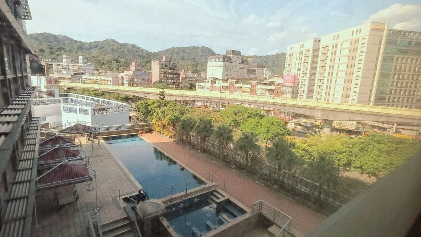 Ein Pool auf dem Dach mit Blick auf eine Stadtansicht, darunter Gebäude und eine Brücke.