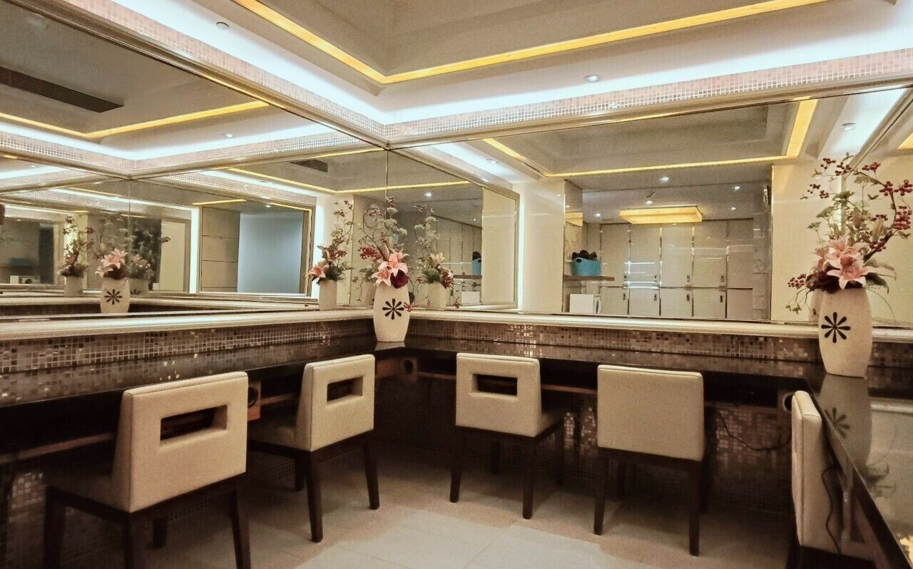 Un bagno moderno con uno specchio grande, uno schienale piastrellato e tre sedie.