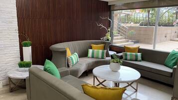 A modern lounge area with a curved grey sofa, a round white table, and a seating area with cushions.