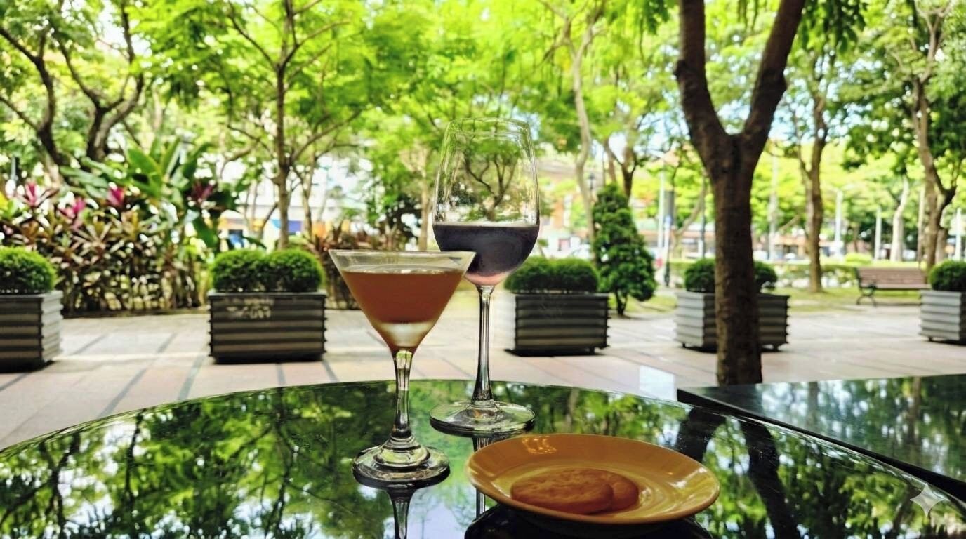 A table with two glasses of a beverage and a plate with a pastry, set outdoors with trees and a pathway in the background.