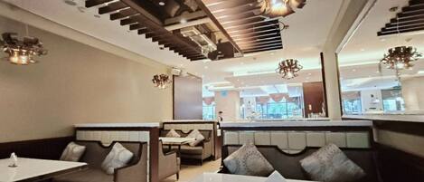 A restaurant with booths and tables, modern lighting fixtures, and a view of the outside.