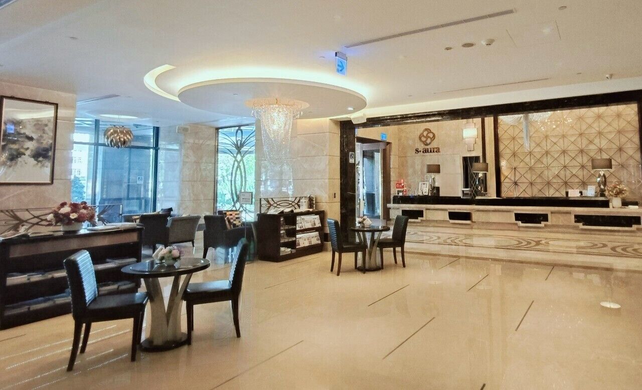 Vestíbulo de hotel con mostrador de recepción, zona de estar y un candelabro.