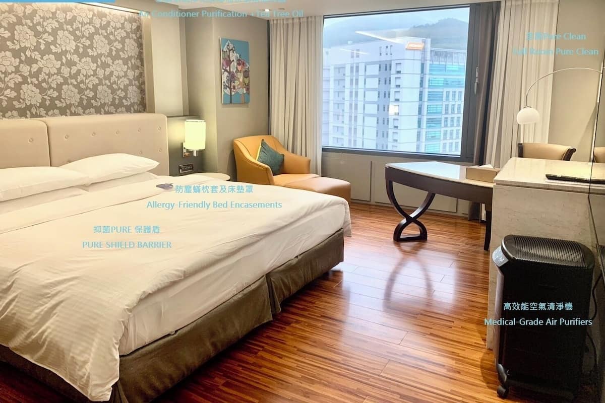 Ein Hotelzimmer mit einem großen Bett, einem Schreibtisch, einem Stuhl und einem Fenster mit Blick auf die Stadt.