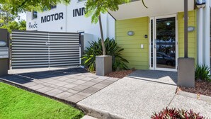Un bâtiment moderne doté d’une entrée sécurisée par un portail, d’un espace d’accueil et d’une enseigne indiquant « MOTOR INN ».