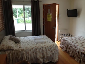 A room with two beds, a TV, and a window with curtains. - Palms Oasis Motel (Coopernook)