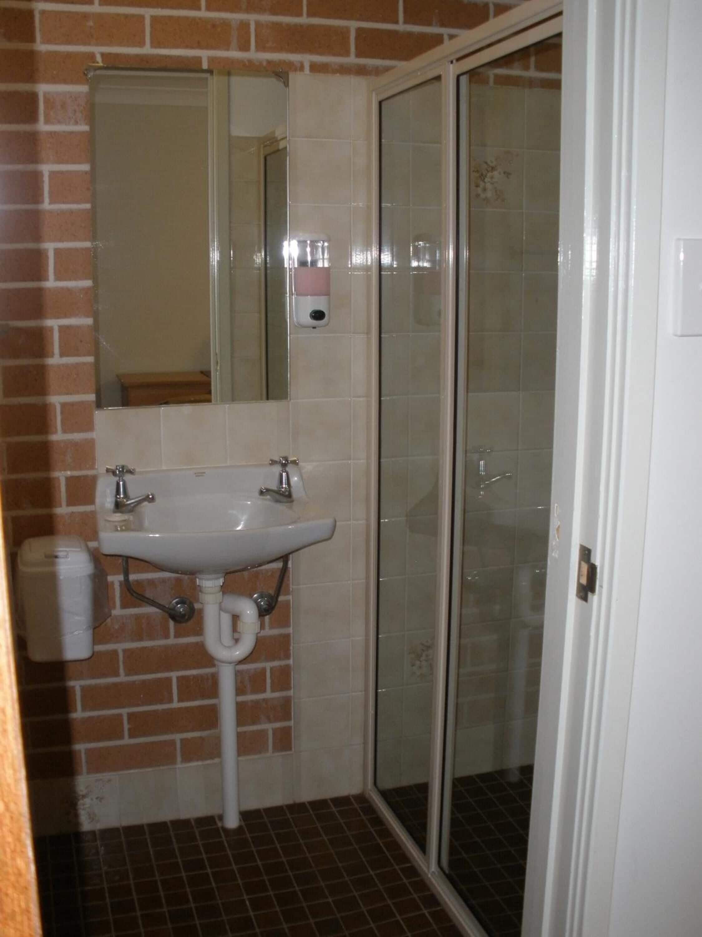 A bathroom with a white sink, a mirror, and a glass shower enclosure.