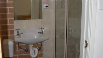 A bathroom with a white sink, a mirror, and a glass shower enclosure.