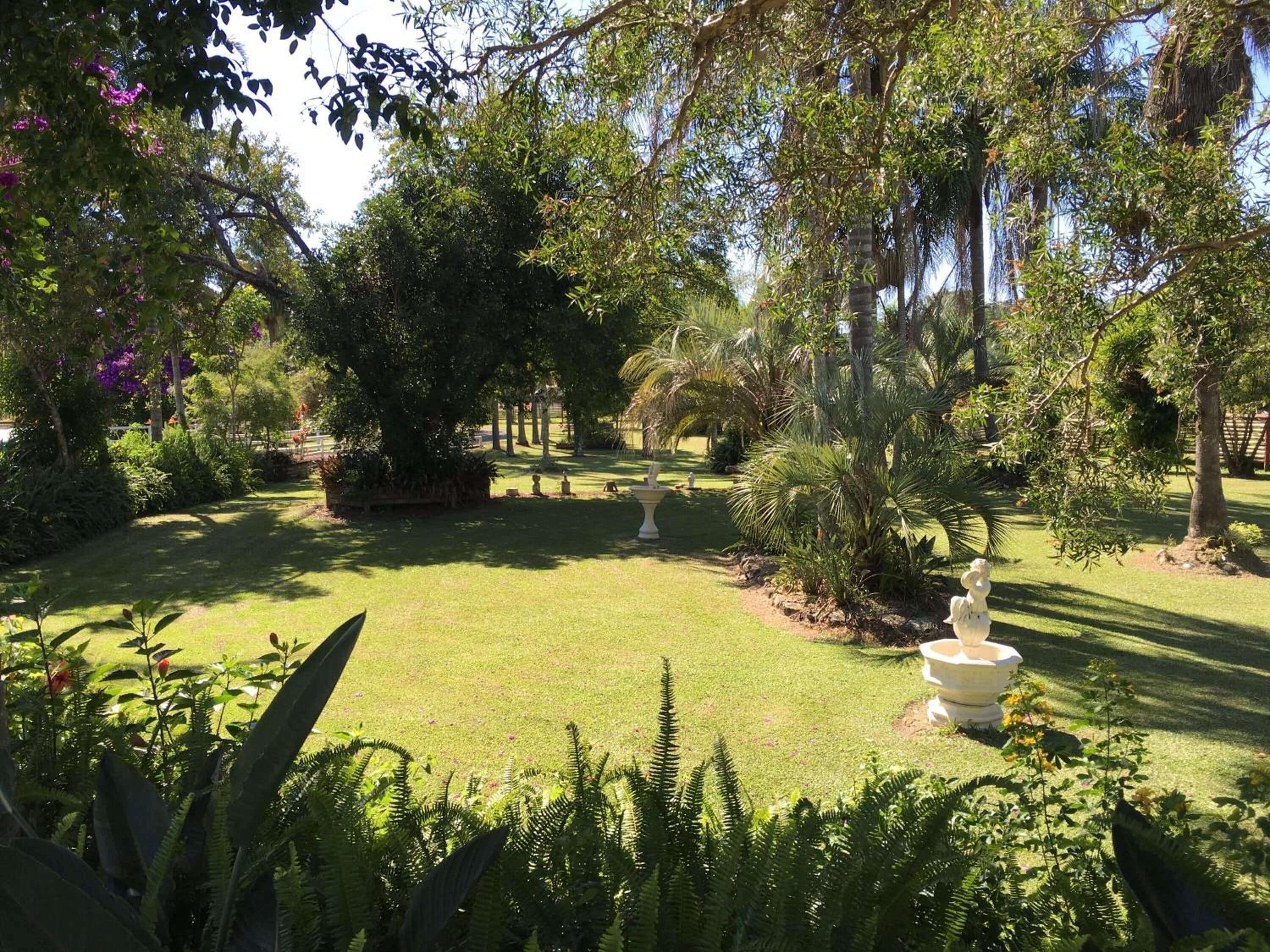 A well-maintained garden with a variety of trees, a lawn, and a central fountain.
