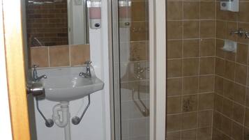 Un baño con ducha, lavamanos y espejo.
