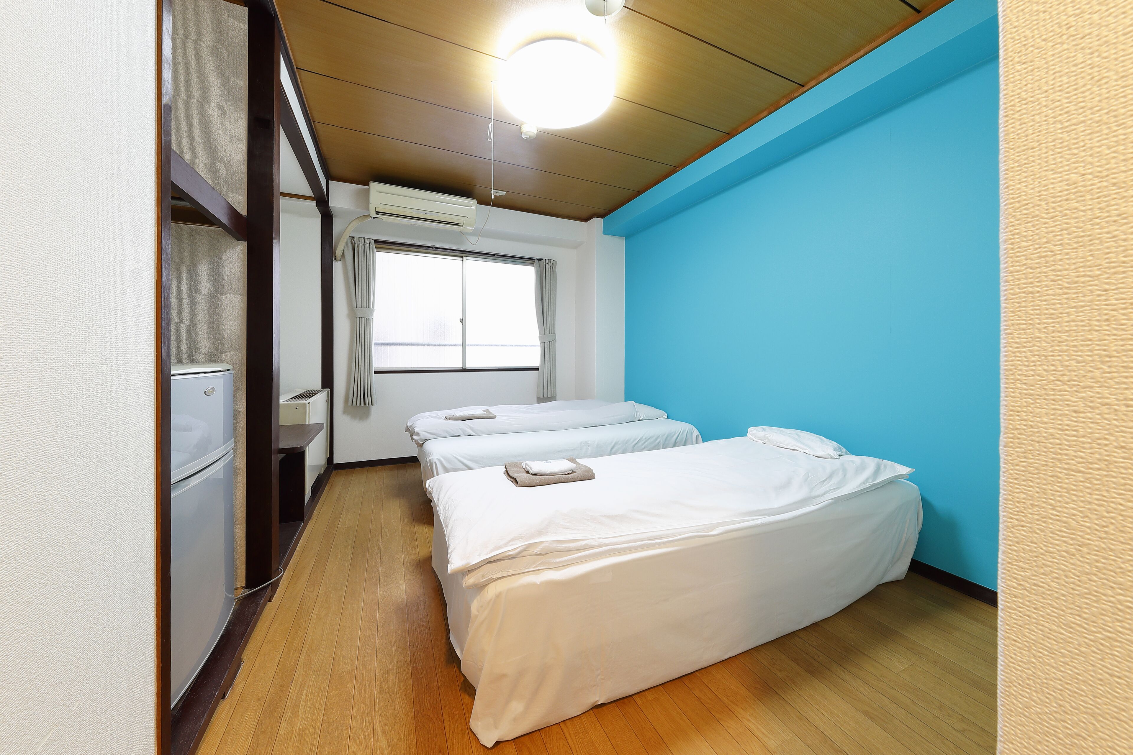 Une chambre avec trois lits, une fenêtre et un appareil de climatisation.