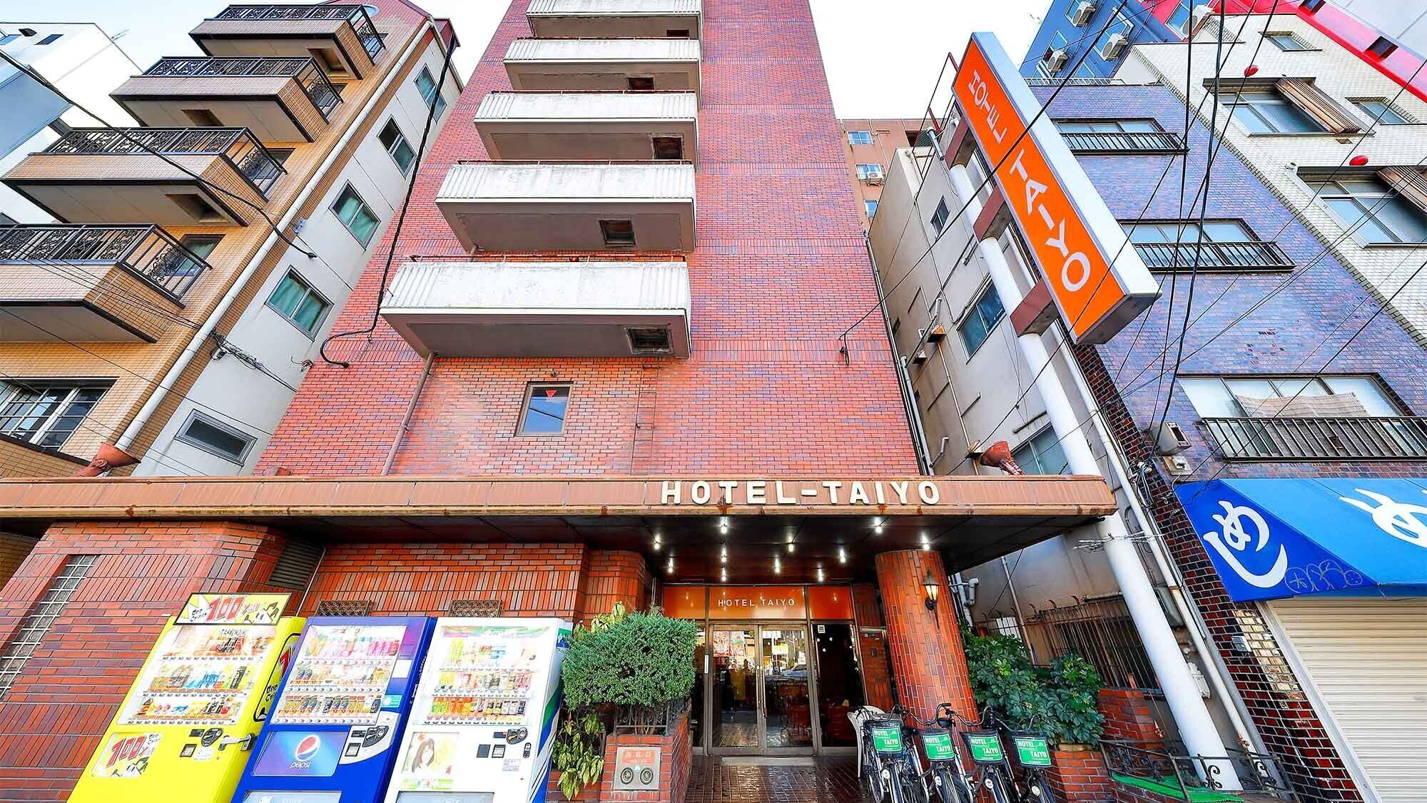 A hotel with a prominent sign, a vending machine, and a bicycle parking area.