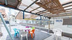 Eine Dachterrasse mit überdachter Sitzgelegenheit, einem Schild für HOTEL TOYO und Blick auf die Stadt.