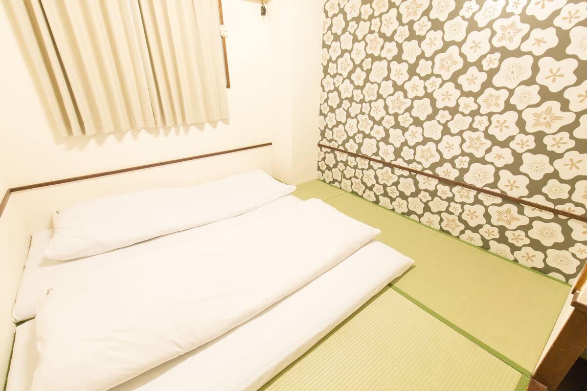 Une pièce avec un lit, un oreiller, un tapis vert et un mur à motifs.