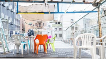 Relax in a casual outdoor space with comfortable seating and a shaded table.