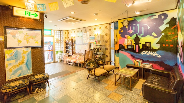 Ein gemütliches Zimmer mit einer Japan-Karte, einem Bett, einem Schreibtisch und einem farbenfrohen Wandbild von Osaka.