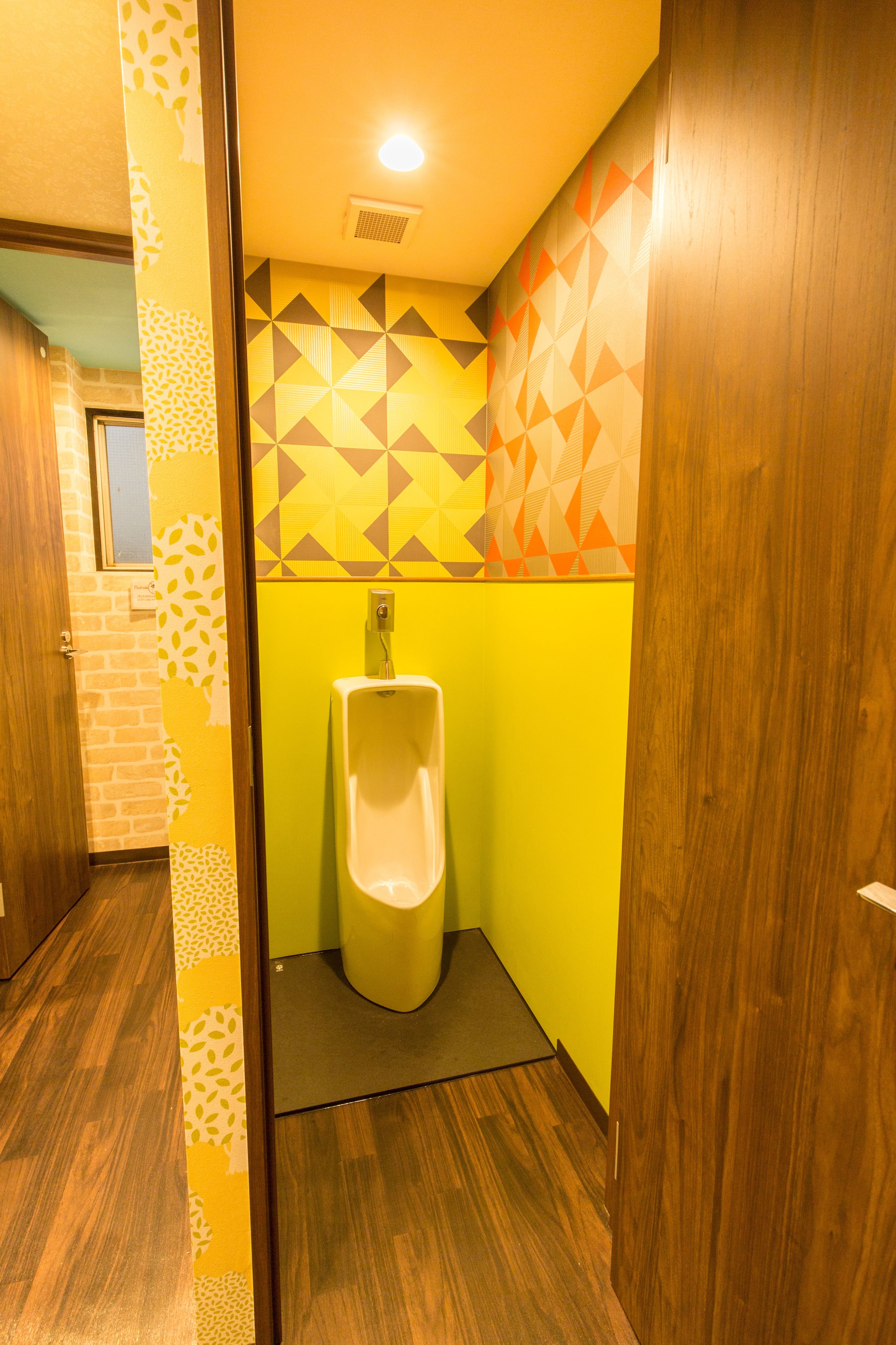 Un lavabo amb orinal, un mur amb dibuixos i terra de fusta.