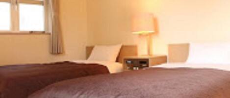A hotel room with two beds, a nightstand, a lamp, and a window with curtains.
