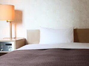 Une chambre d’hôtel avec un lit, une table de chevet et une lampe.