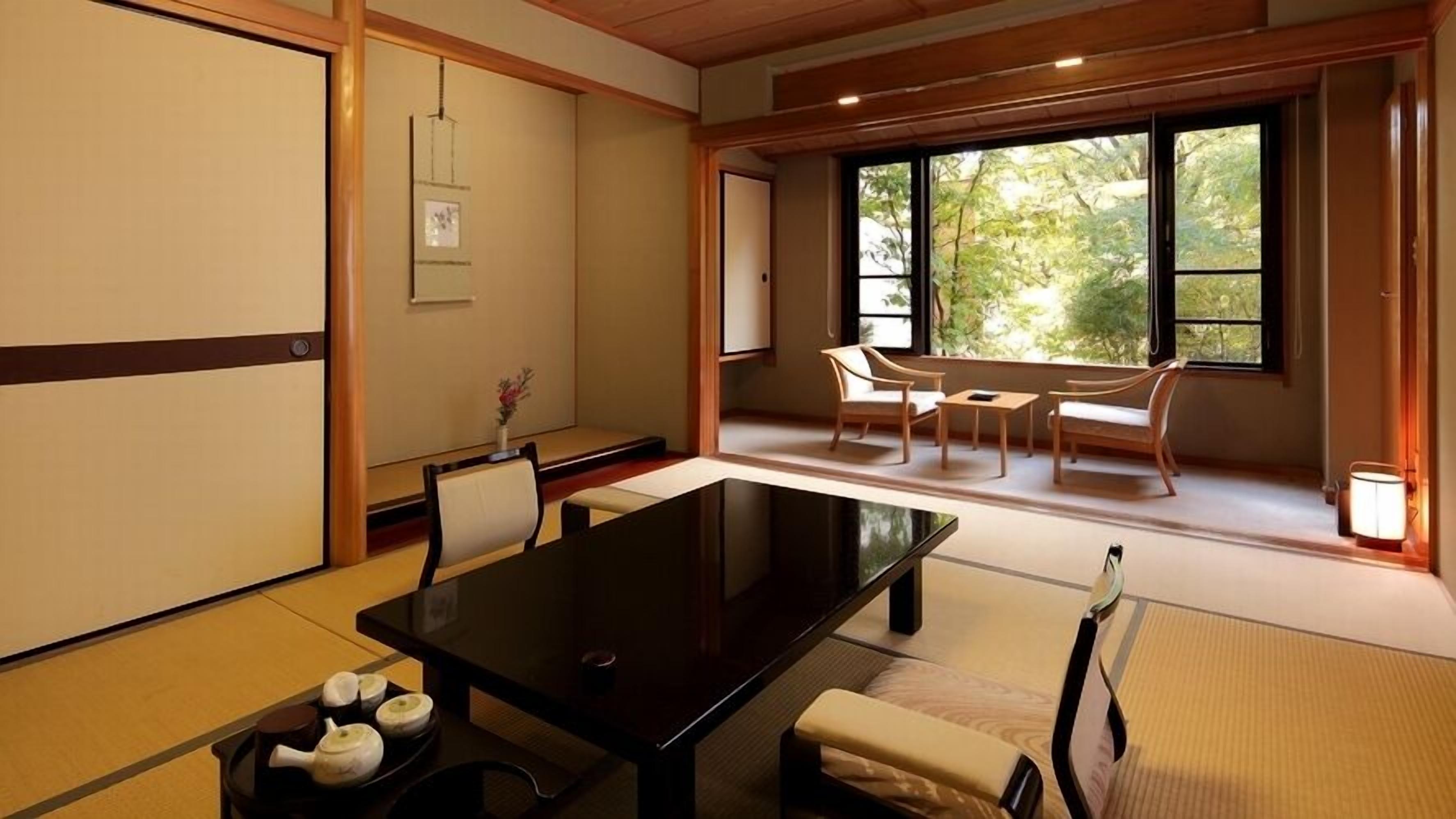 Een traditionele Japanse kamer met tatami vloerbedekking, een lage tafel, stoelen en een schuifdeur.