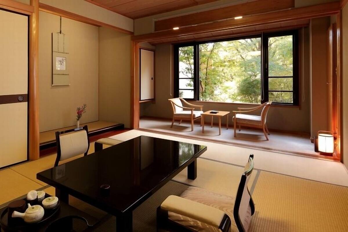 A traditional Japanese-style room with tatami flooring, a low table, chairs, and a sliding door.