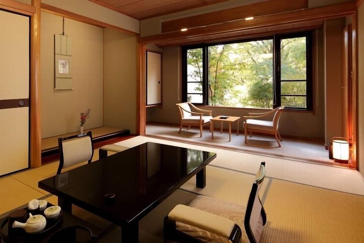 Een traditionele Japanse kamer met tatami vloerbedekking, een lage tafel, stoelen en een schuifdeur.