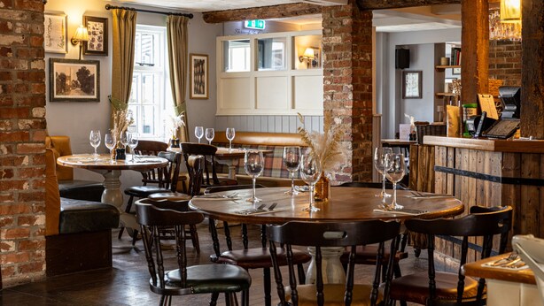 A restaurant interior with brick walls, wooden tables, and leather chairs. - The Countryman Inn (Dorchester)