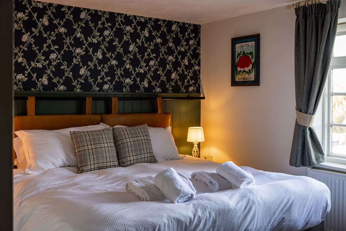 A neatly made bed with pillows, a headboard, a lamp, and a framed picture on the wall.