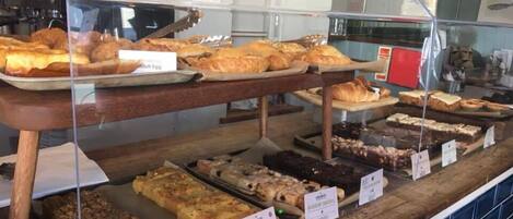 Une vitrine de boulangerie où sont exposés divers produits de boulangerie, comme des croissants, du pain et des pâtisseries.