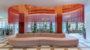 Un área de estar moderna con una disposición de asientos curva, ventanas amplias y plantas en macetas.