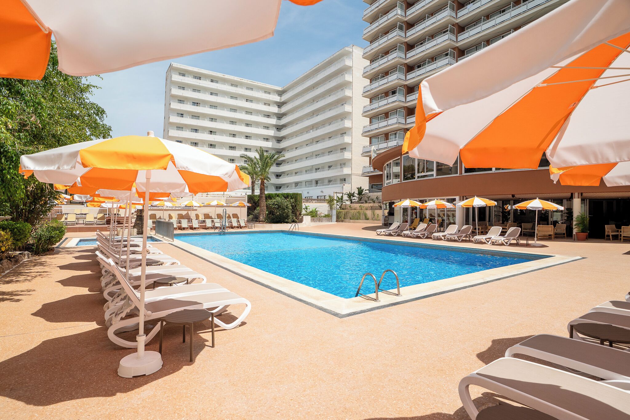Een buitenzwembad, parasols voor strand/zwembad