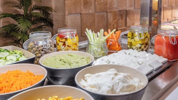 A buffet with various food items including fruits, vegetables, and dips.