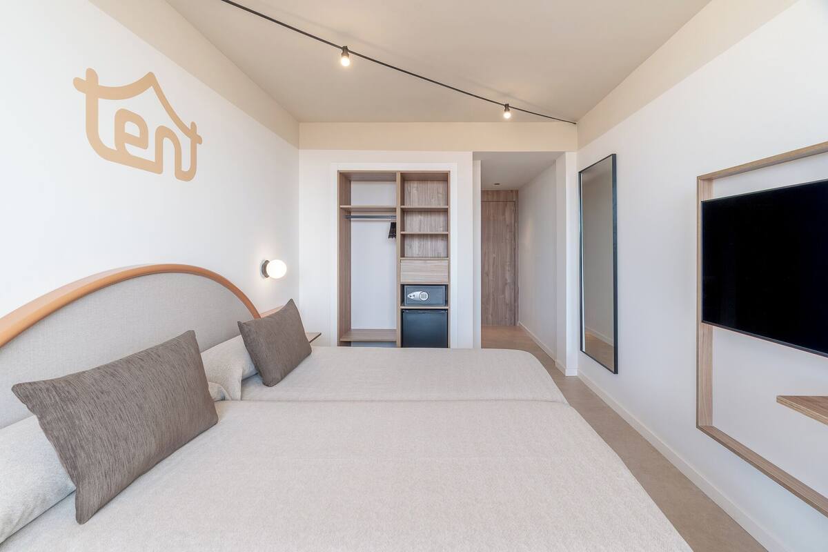 A modern bedroom with a bed, bedside tables, a wardrobe, and a TV.