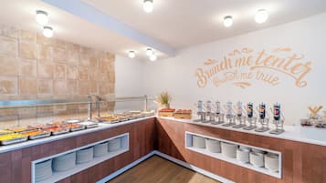 A buffet area with a variety of food options, a glass display case, and a wall with a motivational quote.