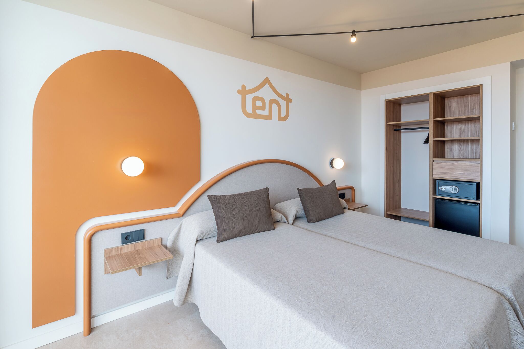 Un dormitorio con cama, mesitas de noche, armario y lámpara de pared.